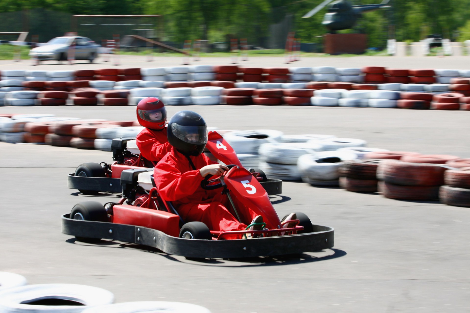 Go carts with drivers wearing red racing on a course