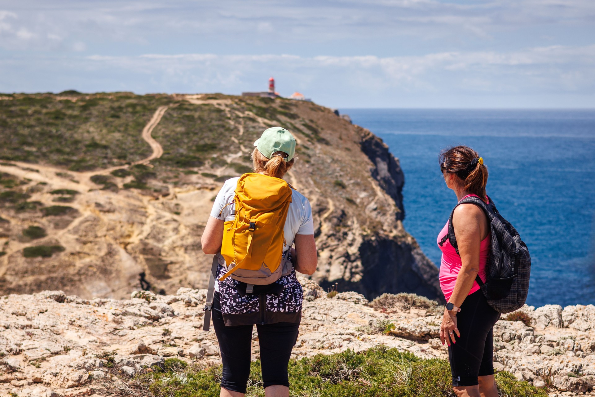Two women hiking along coastline in Algarve, Portugal