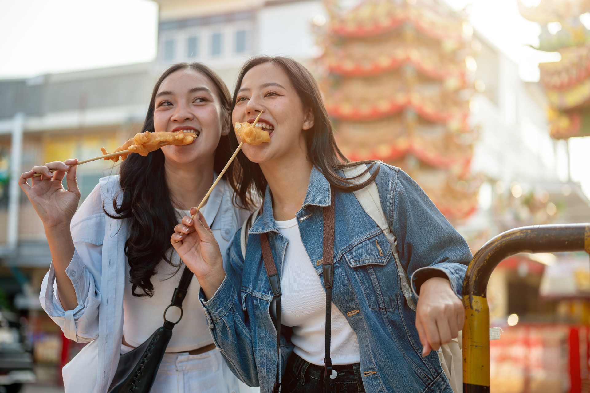 Two beautiful Asian female tourists are enjoy street food in Thailand while exploring the city.